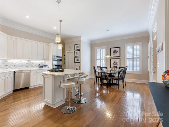 8918 Cotton Press Rd, Charlotte, NC 28277 - kitchen with appliances with stainless steel finishes, a kitchen island, light wood finished floors, white cabinetry, and backsplash