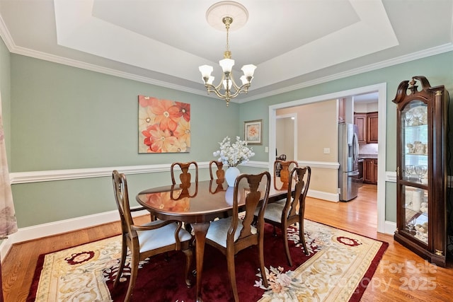 6309 Chamar Cir, Kannapolis, NC 28081 - dining room with a chandelier, a raised ceiling, light wood-style flooring, and crown molding