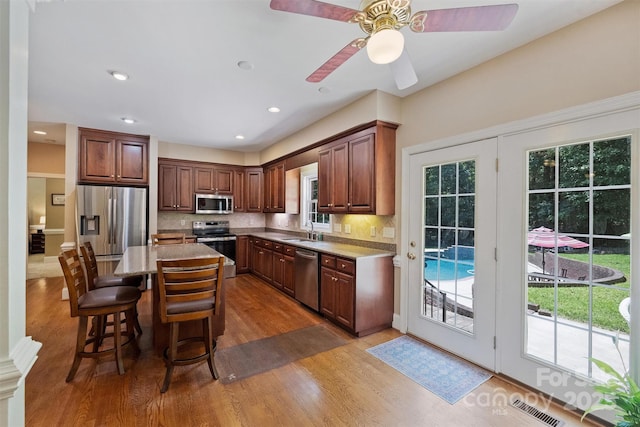 6309 Chamar Cir, Kannapolis, NC 28081 - kitchen featuring stainless steel appliances, wood finished floors, tasteful backsplash, a breakfast bar, and ceiling fan