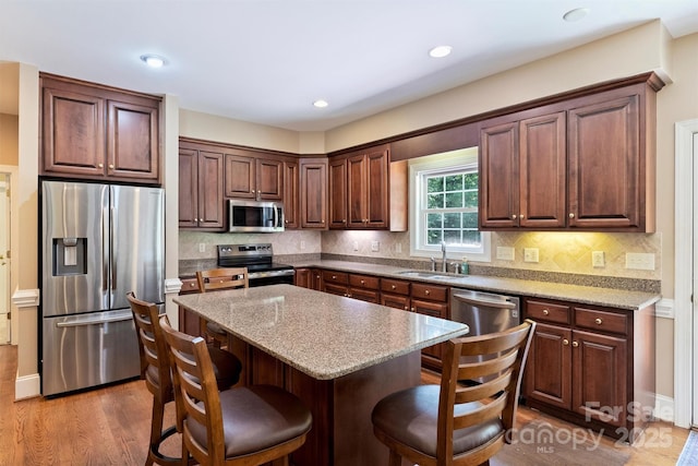 6309 Chamar Cir, Kannapolis, NC 28081 - kitchen featuring appliances with stainless steel finishes, a kitchen breakfast bar, wood finished floors, a center island, and decorative backsplash