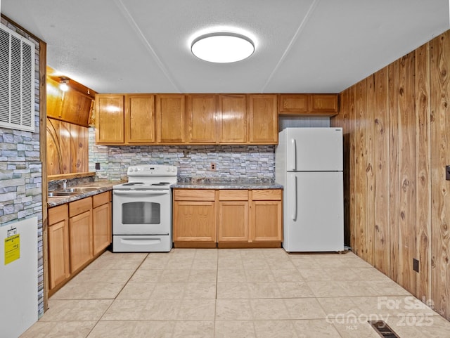 70 John Delk Rd, Hendersonville, NC 28792 - kitchen with white appliances, wood walls, backsplash, dark stone counters, and brown cabinetry