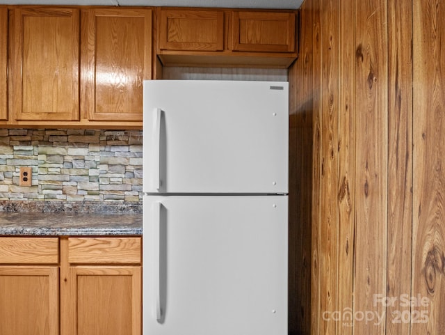 70 John Delk Rd, Hendersonville, NC 28792 - kitchen featuring freestanding refrigerator, dark countertops, tasteful backsplash, brown cabinets, and wood walls