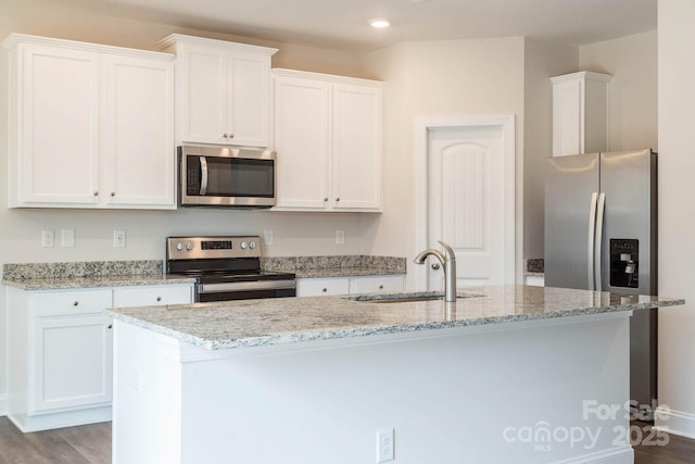 116 Kennford Trl, Troutman, NC 28166 - kitchen with appliances with stainless steel finishes, white cabinets, a center island with sink, light stone countertops, and recessed lighting