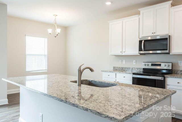116 Kennford Trl, Troutman, NC 28166 - kitchen featuring stainless steel appliances, white cabinets, a chandelier, wood finished floors, and light stone counters