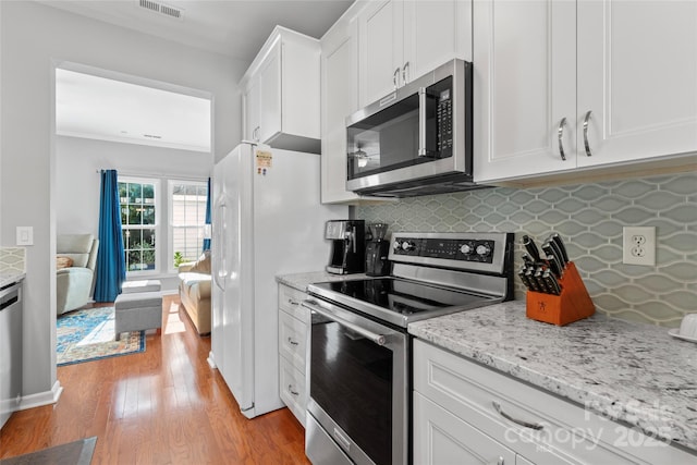 4103 Christine Ln Unit E, Waxhaw, NC 28173 - kitchen with stainless steel appliances, light wood-type flooring, white cabinets, backsplash, and light stone countertops