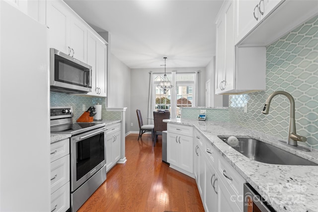 4103 Christine Ln Unit E, Waxhaw, NC 28173 - kitchen featuring stainless steel appliances, wood finished floors, white cabinetry, decorative backsplash, and a chandelier