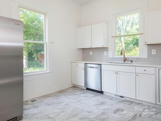 110 College St, Marshville, NC 28103 - kitchen featuring appliances with stainless steel finishes, light countertops, decorative backsplash, white cabinetry, and ornamental molding
