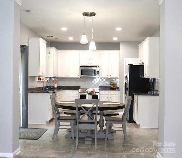 3092 S Legacy Park Blvd, Fort Mill, SC 29707 - kitchen featuring appliances with stainless steel finishes, dark countertops, decorative backsplash, white cabinetry, and pendant lighting