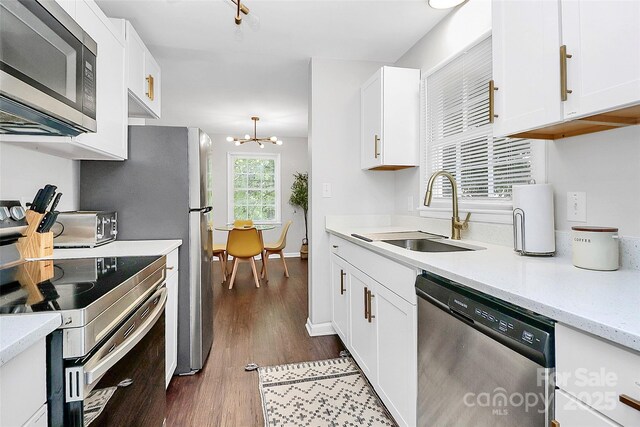 3909 Woodbriar Trl, Charlotte, NC 28205 - kitchen with appliances with stainless steel finishes, dark wood-style floors, white cabinetry, a chandelier, and light stone counters