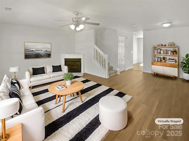 5163 Ficus Tree Ln, Charlotte, NC 28215 - living room featuring wood finished floors, stairway, ceiling fan, and a glass covered fireplace