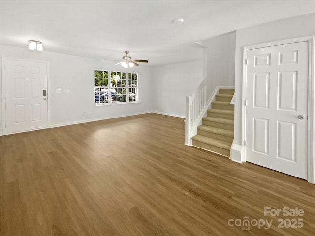 5163 Ficus Tree Ln, Charlotte, NC 28215 - unfurnished living room with wood finished floors, a ceiling fan, and stairs