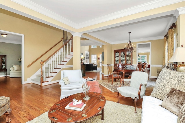 13824 Glen Abbey Dr, Charlotte, NC 28278 - living room featuring wood finished floors, stairway, a chandelier, crown molding, and ornate columns