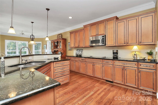 13824 Glen Abbey Dr, Charlotte, NC 28278 - kitchen featuring stainless steel microwave, brown cabinets, ornamental molding, pendant lighting, and light wood-style flooring