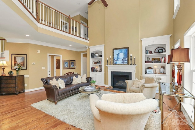 13824 Glen Abbey Dr, Charlotte, NC 28278 - living room featuring a towering ceiling, built in shelves, wood finished floors, a fireplace, and ceiling fan