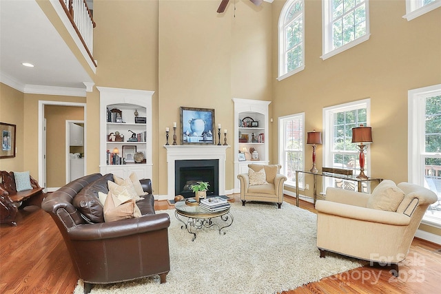 13824 Glen Abbey Dr, Charlotte, NC 28278 - living room with wood finished floors, built in features, crown molding, a fireplace, and a high ceiling