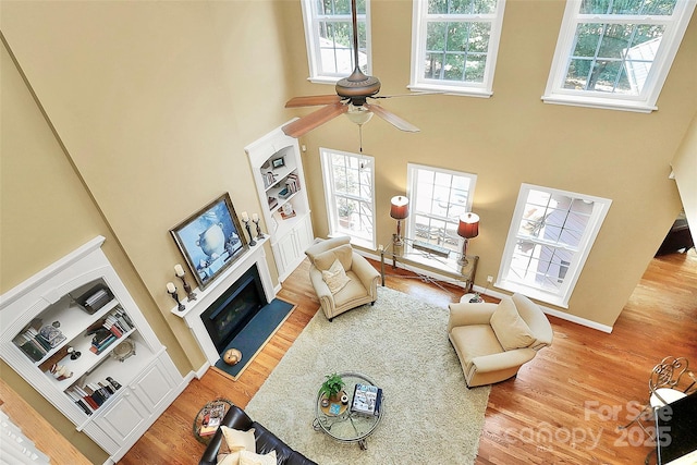 13824 Glen Abbey Dr, Charlotte, NC 28278 - living area featuring a high ceiling, a fireplace with flush hearth, wood finished floors, built in shelves, and ceiling fan