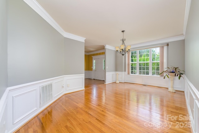 7737 Pleasant Valley Dr, Harrisburg, NC 28075 - unfurnished room featuring a chandelier, ornamental molding, a decorative wall, light wood-type flooring, and a wainscoted wall