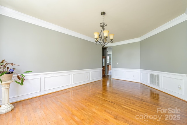 7737 Pleasant Valley Dr, Harrisburg, NC 28075 - spare room featuring a chandelier, ornamental molding, light wood-style floors, a wainscoted wall, and a decorative wall