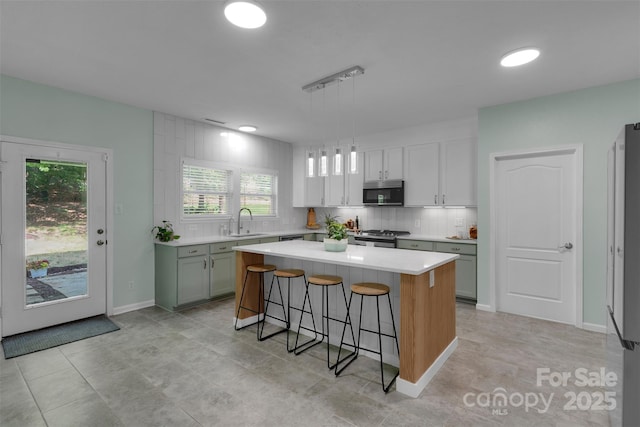 2926 Royal Fern Ln, Charlotte, NC 28215 - kitchen featuring appliances with stainless steel finishes, a breakfast bar area, decorative backsplash, light countertops, and a center island