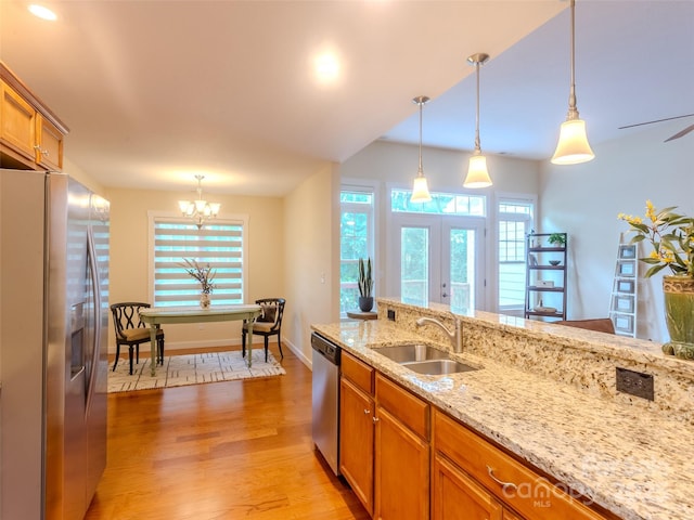 29 Kaylor Dr, Arden, NC 28704 - kitchen featuring appliances with stainless steel finishes, brown cabinets, light wood-style floors, hanging light fixtures, and a chandelier