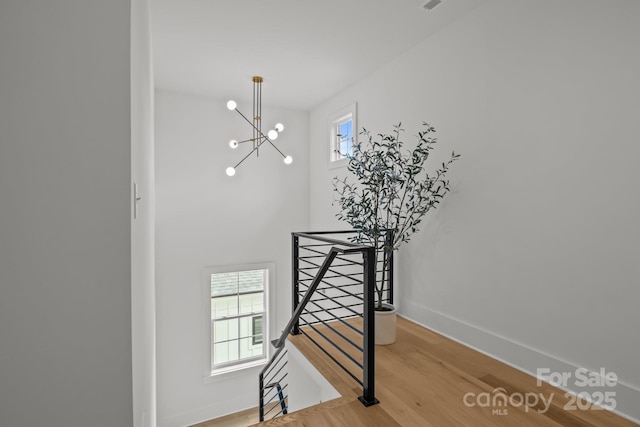 3937 Plainview Rd, Charlotte, NC 28208 - stairs featuring wood finished floors, healthy amount of natural light, and a chandelier