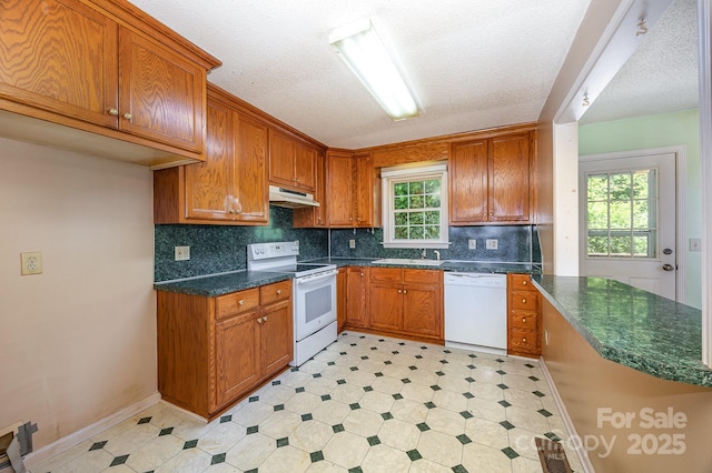38367 Loblolly Ln, New London, NC 28127 - kitchen with white appliances, under cabinet range hood, light flooring, brown cabinets, and a textured ceiling