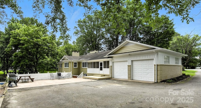 3127 N Center St, Hickory, NC 28601 - view of front of property with brick siding, a chimney, an attached garage, driveway, and a patio
