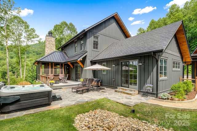 1416 E Clubhouse Rd Unit 73, Sylva, NC 28779 - back of house with a hot tub, board and batten siding, a patio area, a chimney, and a shingled roof