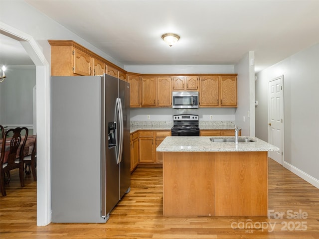 30 Collenwood Rd, Arden, NC 28704 - kitchen with appliances with stainless steel finishes, light wood-type flooring, light stone countertops, a center island with sink, and brown cabinets