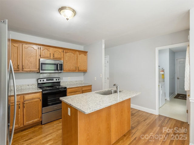 30 Collenwood Rd, Arden, NC 28704 - kitchen featuring stainless steel appliances, light wood-type flooring, a kitchen island with sink, light stone counters, and brown cabinets