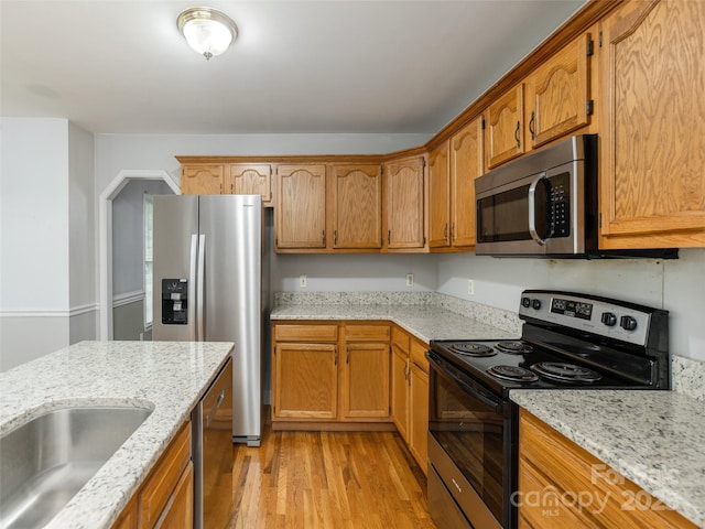 30 Collenwood Rd, Arden, NC 28704 - kitchen featuring appliances with stainless steel finishes, light wood-style floors, light stone counters, and brown cabinets