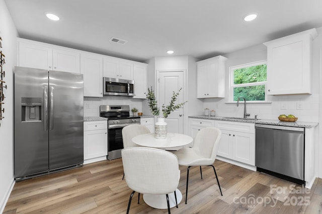 4474 Pebblebrook Cir SW, Concord, NC 28027 - kitchen with stainless steel appliances, decorative backsplash, white cabinets, light stone counters, and recessed lighting