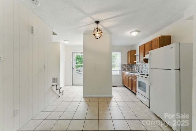 4681-4709 Grassy Creek Rd, Denver, NC 28037 - kitchen with white appliances, brown cabinets, backsplash, light tile patterned floors, and under cabinet range hood