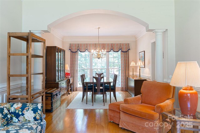 10405 Lady Grace Ln, Charlotte, NC 28270 - dining area featuring arched walkways, wood finished floors, a chandelier, crown molding, and ornate columns
