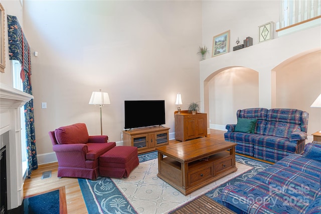 10405 Lady Grace Ln, Charlotte, NC 28270 - living room with a high ceiling, a fireplace, light wood-style floors, and arched walkways