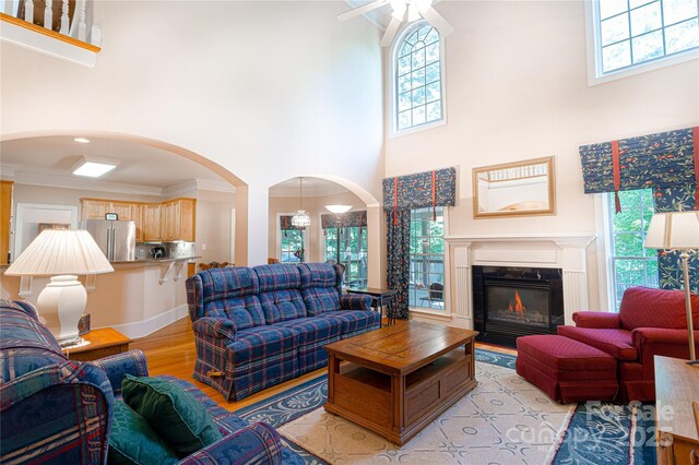 10405 Lady Grace Ln, Charlotte, NC 28270 - living room with a towering ceiling, light wood finished floors, arched walkways, a glass covered fireplace, and ornamental molding