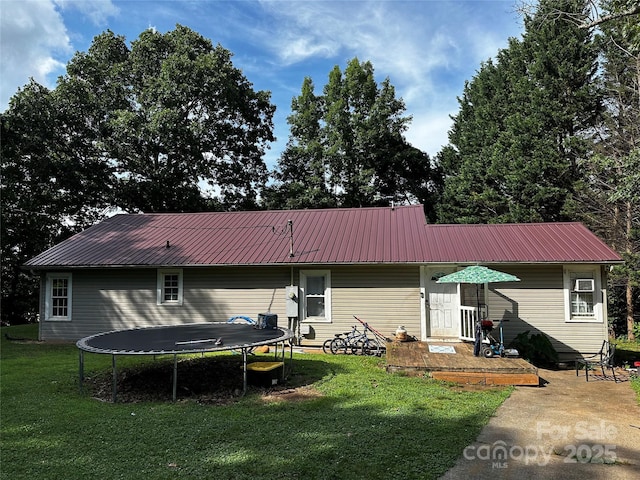 1041 Tomlinson Loop, Connelly Springs, NC 28612 - rear view of property with a trampoline, a lawn, and a metal roof