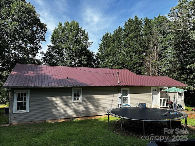 1041 Tomlinson Loop, Connelly Springs, NC 28612 - back of property with a trampoline, a yard, and a metal roof