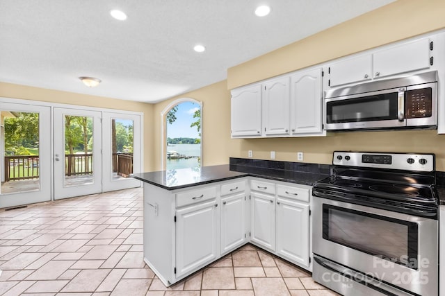 698 Normandy Rd, Mooresville, NC 28117 - kitchen with appliances with stainless steel finishes, a peninsula, dark countertops, white cabinetry, and recessed lighting