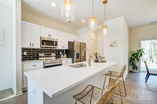 709 Catawba St, Lincolnton, NC 28092 - kitchen with appliances with stainless steel finishes, dark wood-style flooring, backsplash, white cabinetry, and a kitchen island with sink