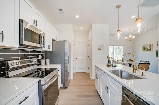 709 Catawba St, Lincolnton, NC 28092 - kitchen featuring appliances with stainless steel finishes, light wood-style floors, white cabinets, decorative backsplash, and recessed lighting