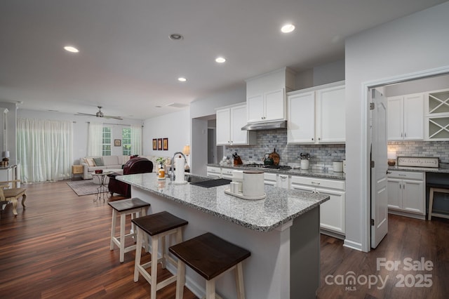 658 Gardenbrook Trl, Belmont, NC 28012 - kitchen featuring under cabinet range hood, backsplash, open floor plan, a kitchen breakfast bar, and light stone countertops