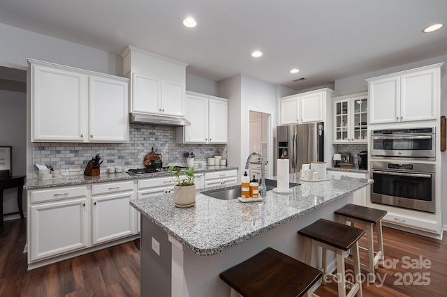 658 Gardenbrook Trl, Belmont, NC 28012 - kitchen with stainless steel appliances, white cabinetry, decorative backsplash, a breakfast bar area, and under cabinet range hood