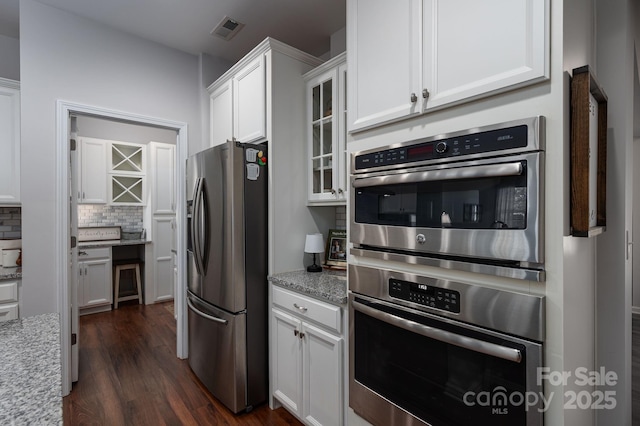 658 Gardenbrook Trl, Belmont, NC 28012 - kitchen with stainless steel appliances, white cabinets, dark wood finished floors, tasteful backsplash, and glass insert cabinets