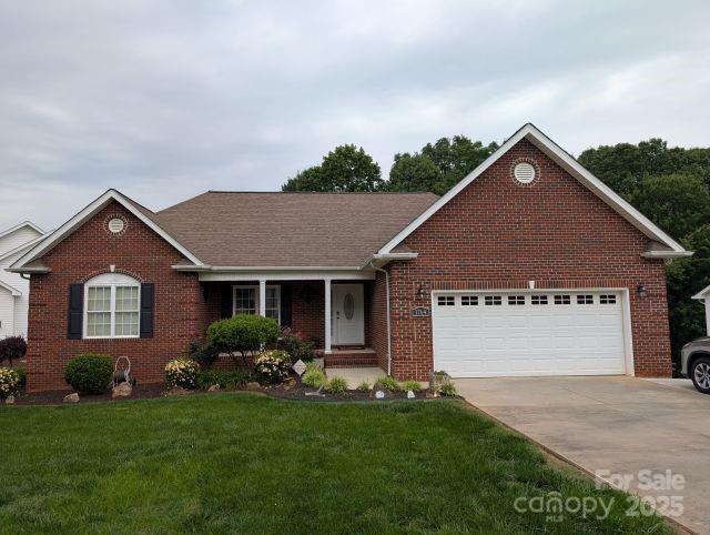 1764 Pipers Ridge Cir NW, Conover, NC 28613 - view of front of home with brick siding, concrete driveway, a front yard, an attached garage, and a shingled roof