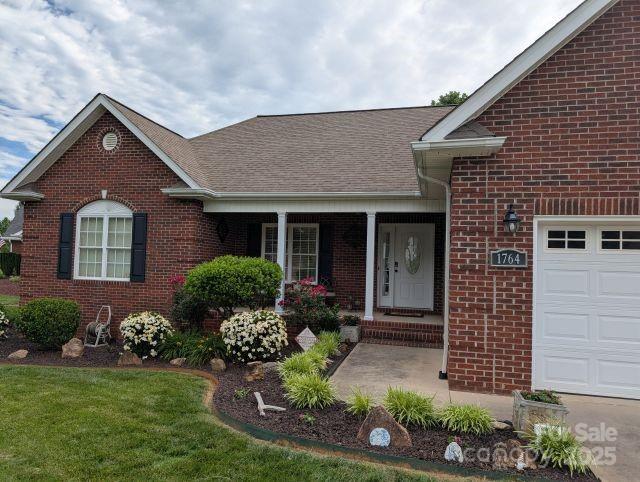 1764 Pipers Ridge Cir NW, Conover, NC 28613 - view of front of property featuring brick siding, a porch, an attached garage, and a front lawn