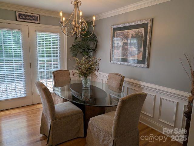 1764 Pipers Ridge Cir NW, Conover, NC 28613 - dining area with a chandelier, a decorative wall, light wood finished floors, crown molding, and a wainscoted wall
