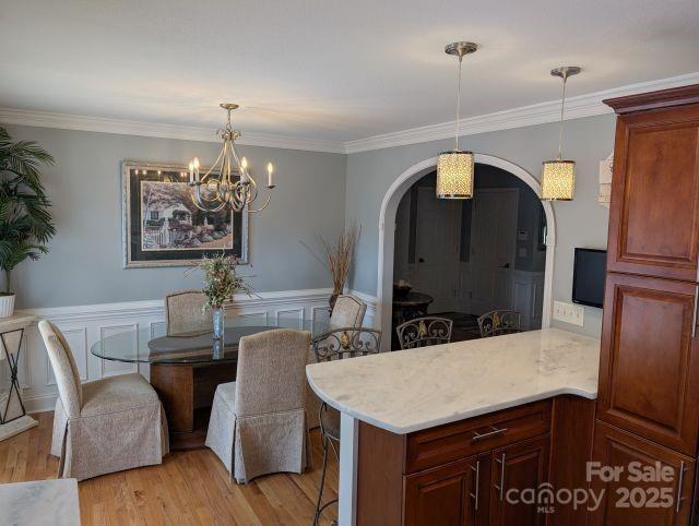 1764 Pipers Ridge Cir NW, Conover, NC 28613 - dining room with arched walkways, light wood-type flooring, a chandelier, crown molding, and wainscoting
