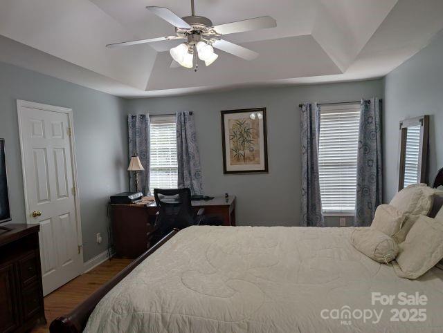1764 Pipers Ridge Cir NW, Conover, NC 28613 - bedroom featuring wood finished floors, a tray ceiling, an office area, and a ceiling fan