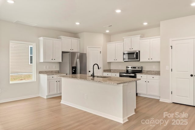 1041 Russell Dr, Winston Salem, NC 27127 - kitchen with appliances with stainless steel finishes, light wood-style flooring, white cabinets, an island with sink, and recessed lighting